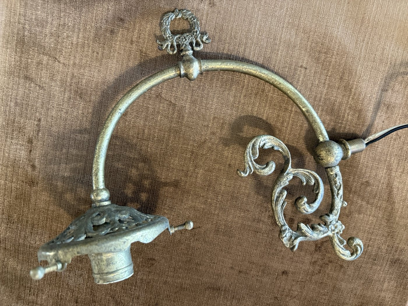 Decorative curved lighting arm with scrollwork and its existing aged finish